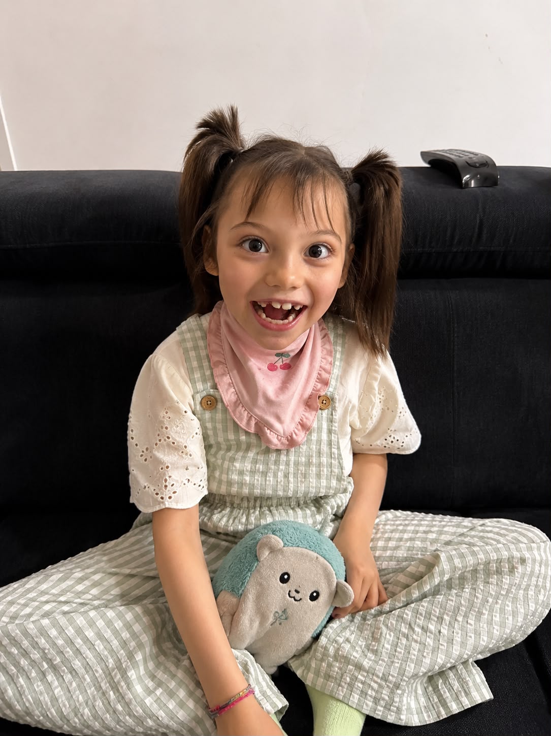Leonor Lopes sitting on a sofa, smiling with a toy in her lap